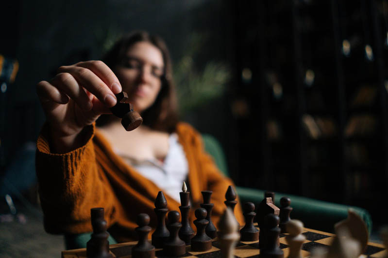 تصویر یک خانم با مهره ها و صفحه شطرنج