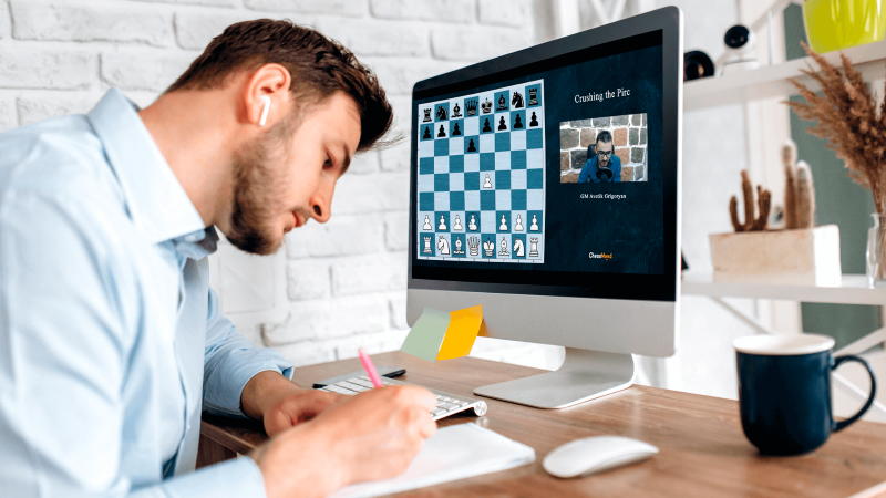 پسری که آنلاین شطرنج بازی می کند و یک لیوان نوشیدنی بر روی میز است